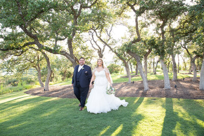 An Austin-based wedding photographer captures a beautiful moment as the bride and groom walk through the trees at their wedding.