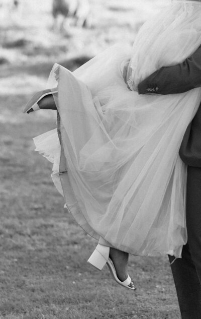 black and white photo of groom lifting up bride