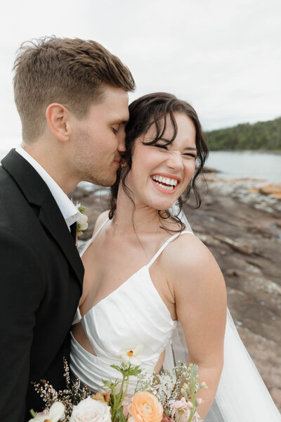 A person leaning in to kiss their partner's cheek on their wedding day 