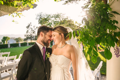 Bride and groom kissing under wisteria at spring wedding in California