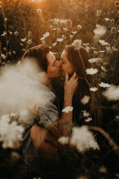 man and woman kissing while surrounded by flowers