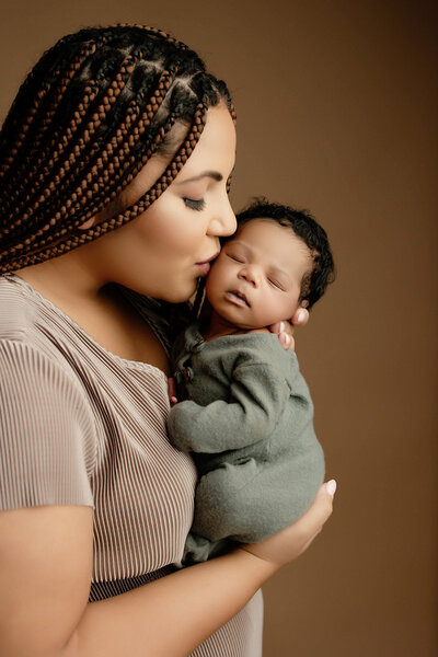 Mother and father smiling at newborn in brightly lit portrait