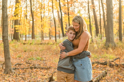 Mom hugging her son in the fall Illinois woods by Chicago family photographer Kristen Hazelton