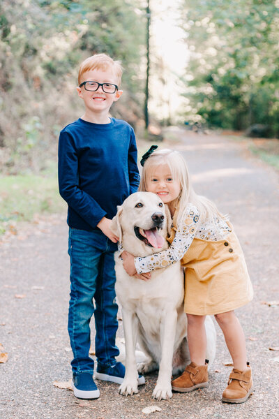 A daughter and son hug on their family lab during their family session.