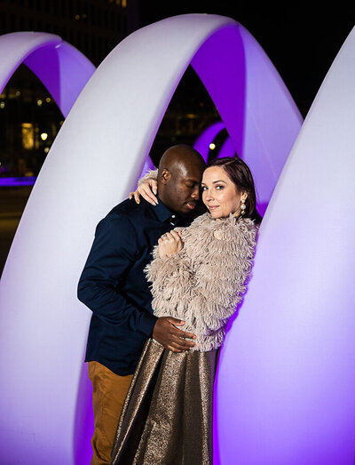 evening engagement session of multicultural couple  in purple sculpture Minneapolis Minnesota