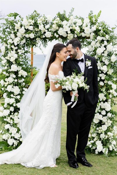 A couple with their arms wrapped together smiling and touching heads 