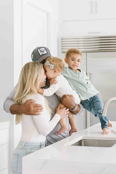 young family hugging each other in kitchen