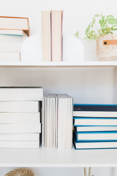 A white bookshelf with stacks of books