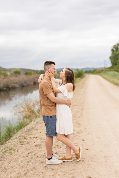 couple in neutral colors hugging along a dirt road