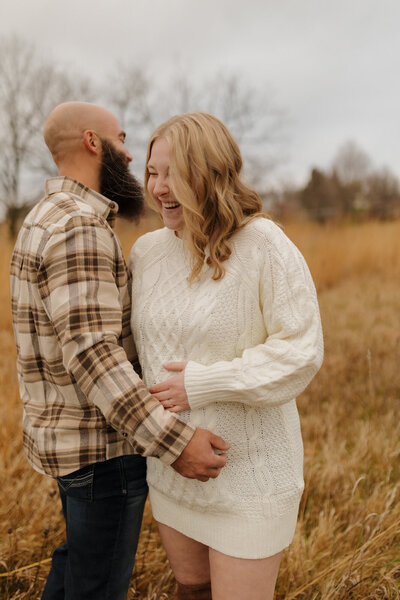 mom and dad laugh during fall maternity photos in mount horeb wisconsin 