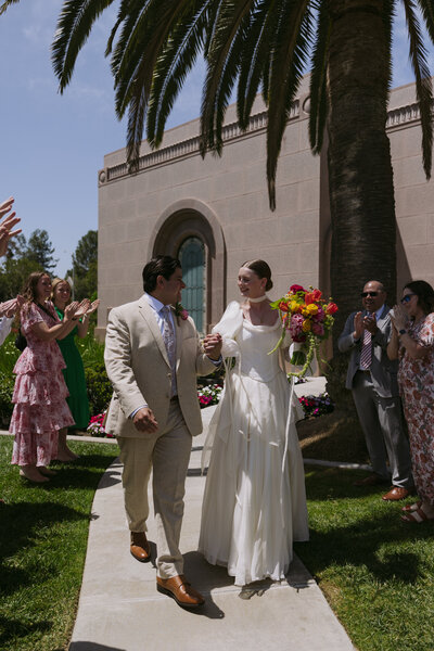 Regan and Yered exiting their sealing at the Newport LDS Temple with all of their family and friends lines up around them.