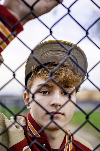 baseball teen boy behidn fence