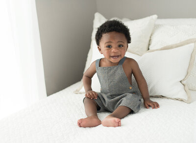 1 year old sitting on bed at home for a baby milestones photography session