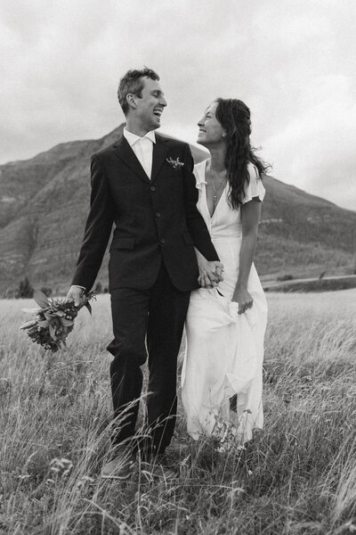Bride and groom hold hands and smile at each other captured by cranbrook photographers