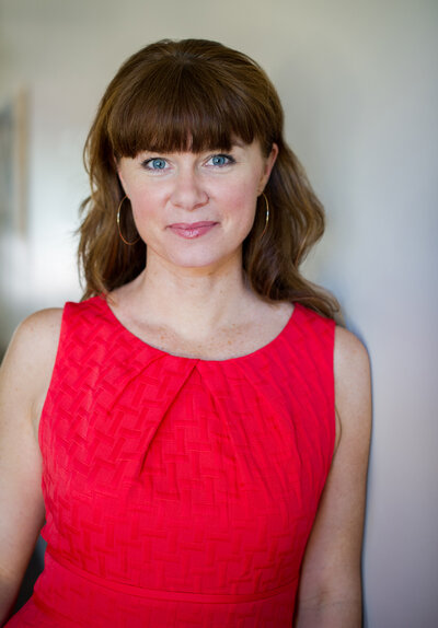 Professional Business headshot of marketing expert Leona Laurie wearing red dress.