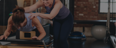 woman assisting a client on a Pilates reformer 