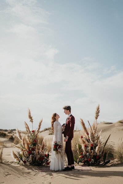 Bride and groom hold hands at their Oregon elopement ceremony location in the dunes