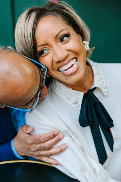 Man playfully nuzzling a smiling woman’s neck as she gazes into the distance during a romantic Paris couples photoshoot near the Eiffel Tower and in the Latin Quarter.
