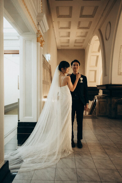 Bride and groom hold hands inside an elegant, historic hallway on the Sunshine Coast.