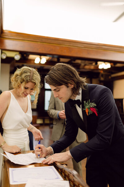 Bride and groom signing their marriage certificate during their New York City wedding ceremony.