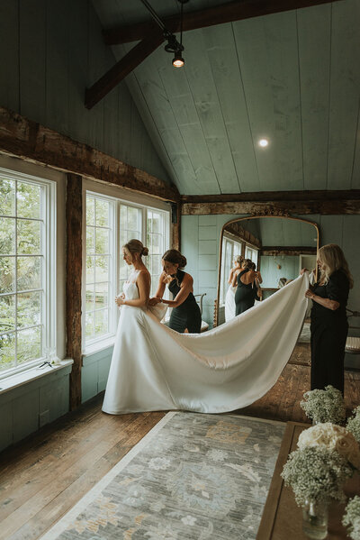 Bridesmaid helps bride buckle her shoes while getting ready on her wedding day