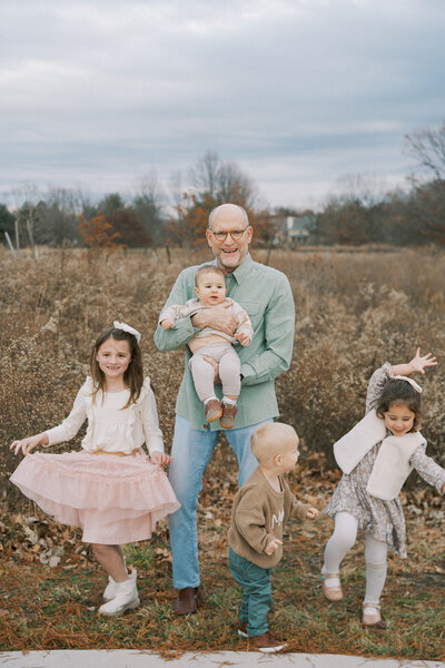 a dad smiling while standing with his kids