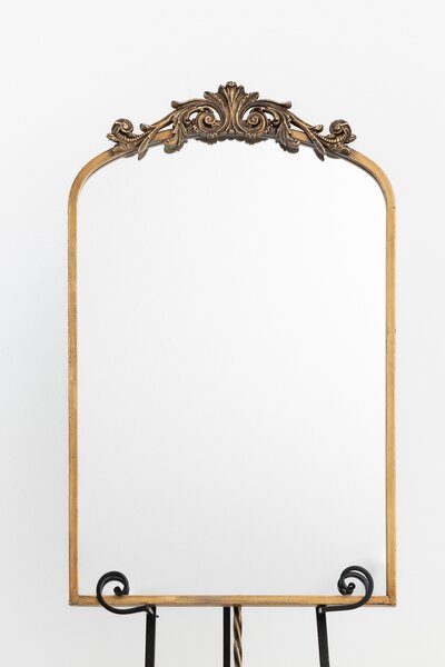 Gold arched mirror with decorative scrollwork on black easel stand