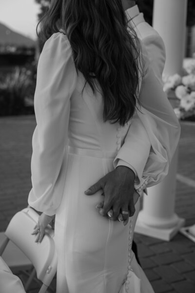 Intimate moment between the bride and groom holding hands, in black and white.