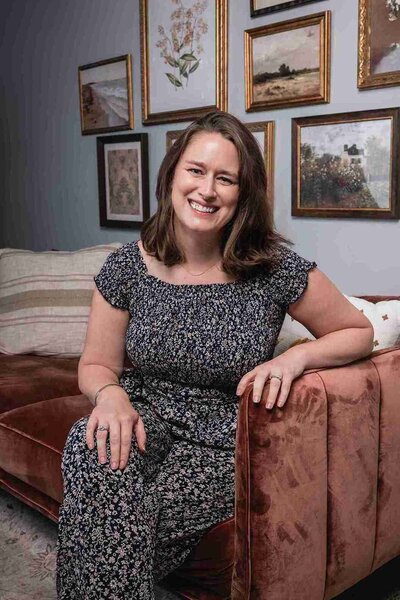 A therapist named Lauren Strine sits on a couch, surrounded by framed pictures on the wall behind her in Atlanta, Georgia.
