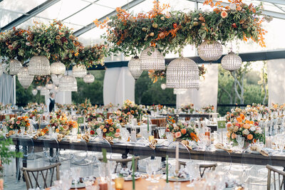 Eye-catching oversized chuppah overflowing with fall florals featuring dahlias, garden roses, rain tree pods, and fall greenery. Autumnal hues of terra cotta, dusty pink, copper, and yellow create this statement wedding piece. Designed by Rosemary and Finch in Nashville, TN.