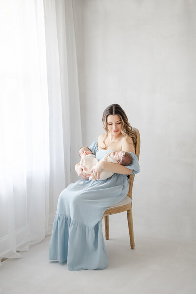 Luxury newborn portrait of Tampa baby twins swaddled in neutral tones sitting next to window