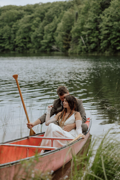 bride and groom sitting in a canoe embracing each other on a lake