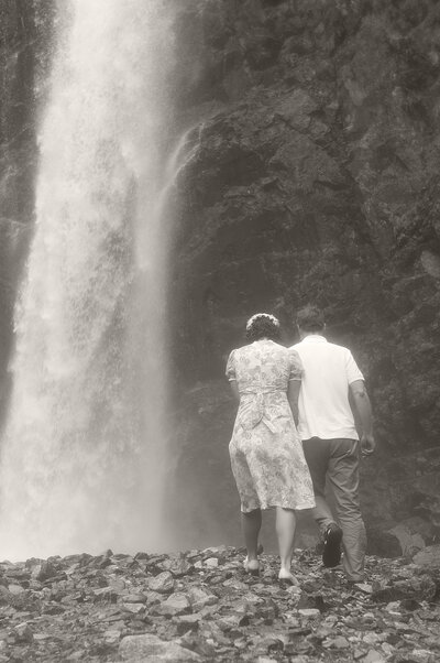 Vintage style photo of a couple walking behind a waterfall