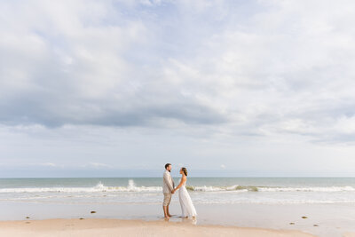 "Bride and groom hold hands on Carolina Beach"