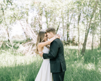 bride and groom embracing by trees near the Gallatin River