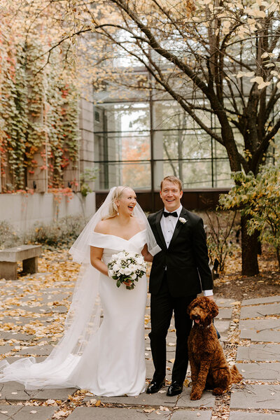 Wedding photography of blonde bride and groom looking at the camera while standing next to their dog at Missouri History Museum