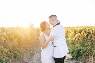 bride and groom eskimo kisses in vineyard at sunset
