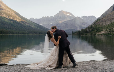 A wedding couple kisses in front of a gorgeous mountain view at sunset.