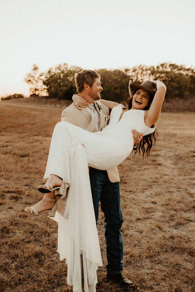 bride wears grooms cowboy hat at their ranch wedding