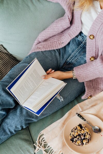 Woman's lap while sitting on a coach and reading an open book