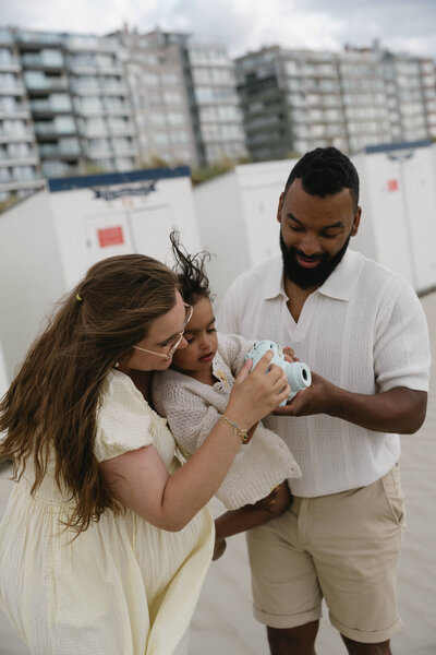 Koppel houdt dochtertje vast die speelt met speelgoedcamera.