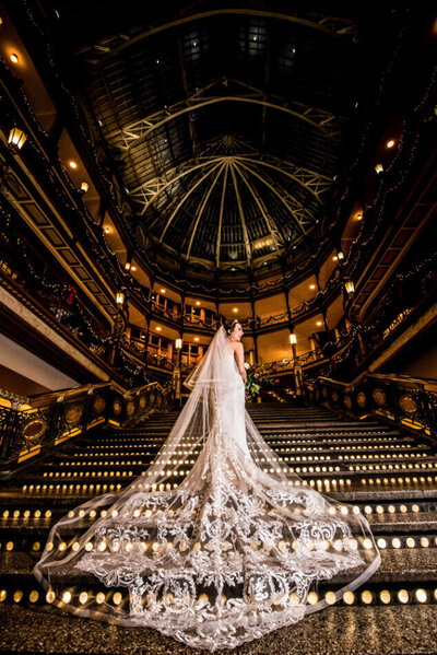 bride standing on the steps at the hyatt at the arcade in downtown cleveland showing off the back of her amazing dress