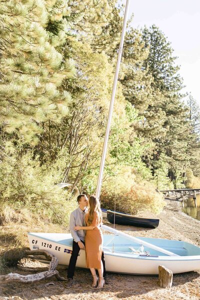engaged couple standing in front of boat