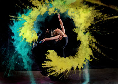 Blue and yellow streams of color flow from the dancer's hands.