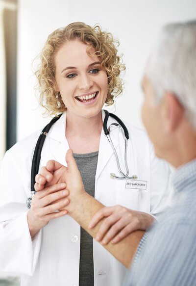 Female doctor holding arm of  grey haired person