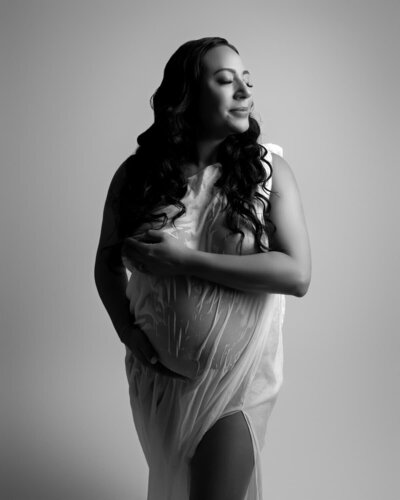 Maternity portrait in wet-look sheer fabric with backlighting – high-end studio photo by Hello Photography in Austin

