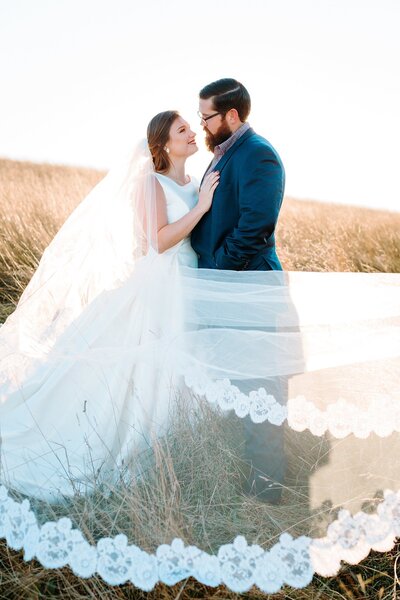 Wedding photo in Boone, NC of a bride and groom standing in a field and smiling at each other.