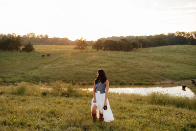 photo of woman standing in wide open field holding camera
