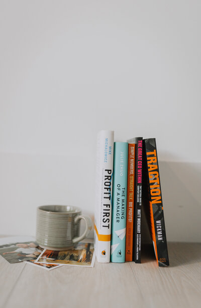 A mug and a stack of books lined up along a wall