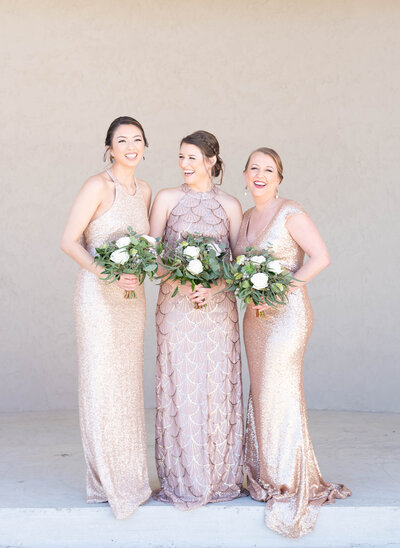 three bridesmaids laughing in gold dresses